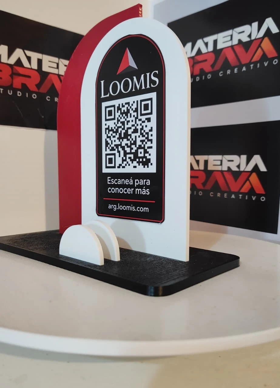 Foto real de un display QR de mostrador con base negra y cuerpo rojo y blanco de Materia Brava